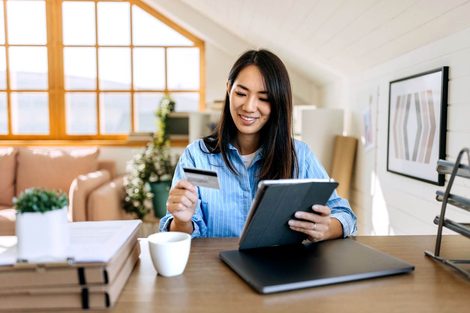 Woman looking at credit card while holding an Ipad